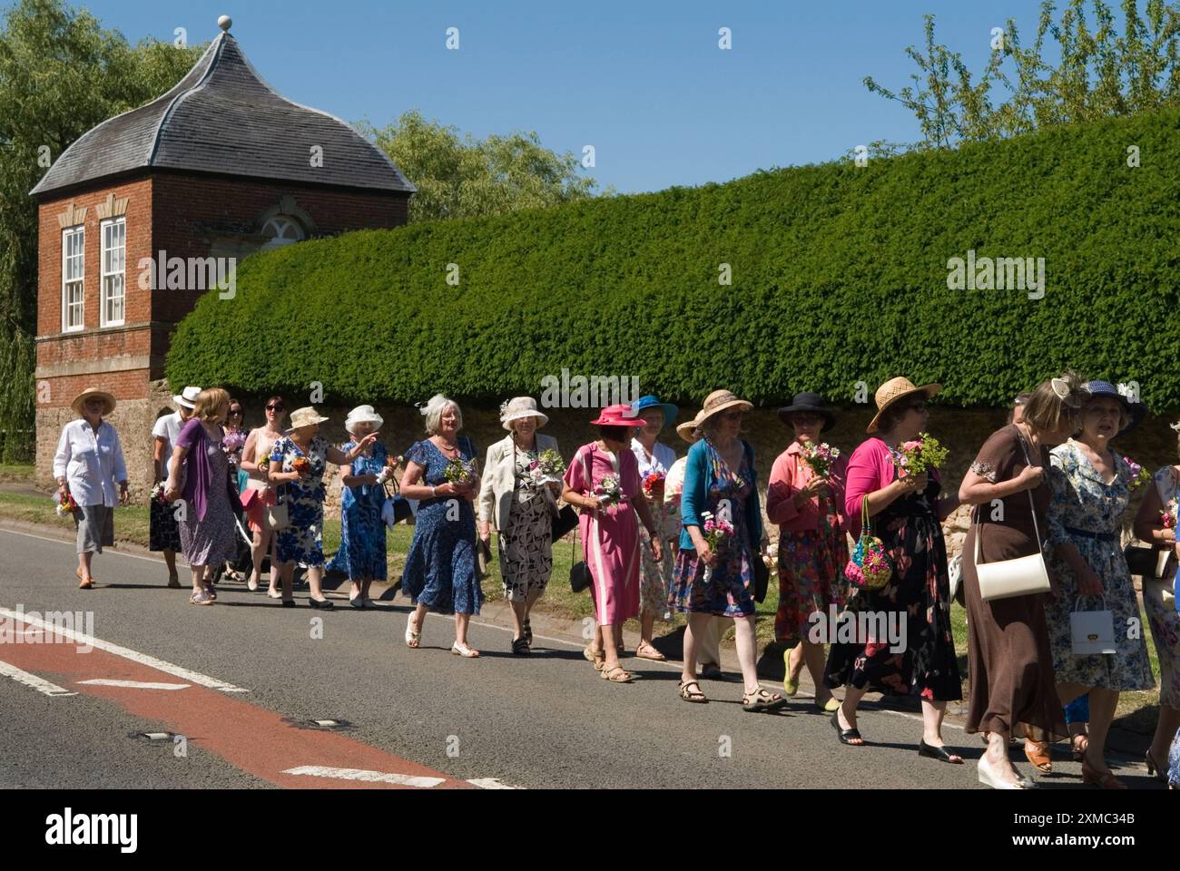 Nether Stowey Female Friendly Society; The Womens Walk il giorno del Club, camminano fino alla tomba nella chiesa di St Marys del loro fondatore, l'uomo d'affari locale Tom Poole. Le donne indossano i loro migliori abiti estivi e cappelli estivi, tutte portano un posey di fiori. Nether Stowey, Somerset, Inghilterra 21 giugno 2014. HOMER SYKES DEGLI ANNI '2010 DEL REGNO UNITO Foto Stock