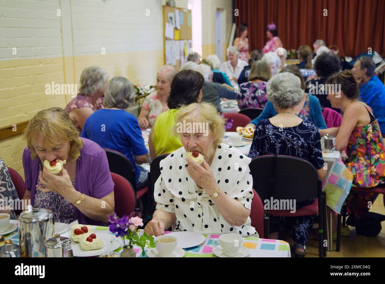 Village Hall a Cream Tea. The Nether Stowey Female Friendly Society; The Womens Walk il giorno del Club. Un tè con panna alla fine dei festeggiamenti pomeridiani costò 5,00 sterline nel 2014. Due donne che mangiano panini alla crema di fragole. Nether Stowey, Somerset, Inghilterra 21 giugno Regno Unito 2010s HOMER SYKES Foto Stock