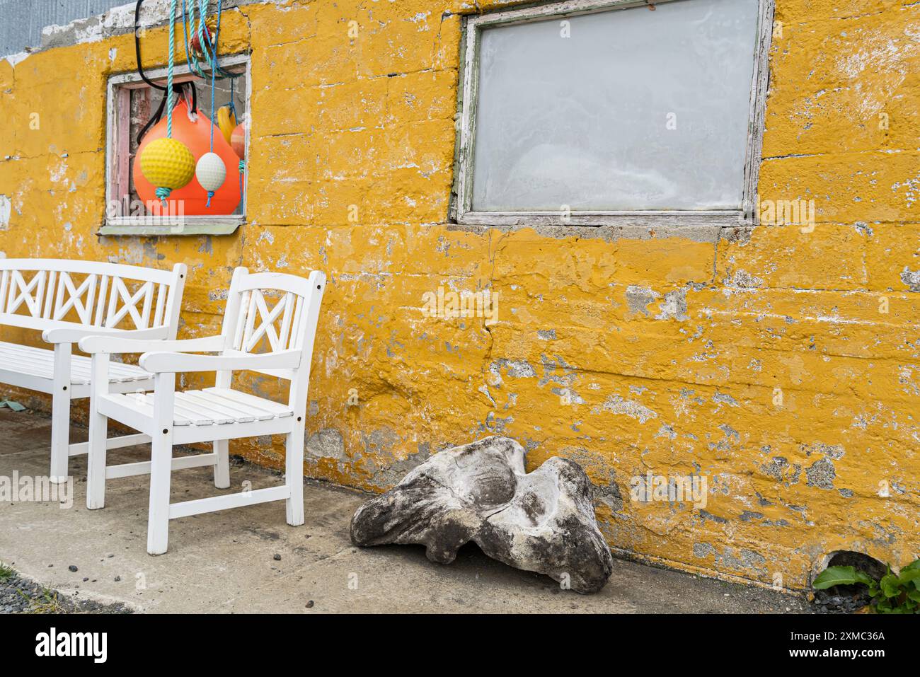 Muro giallo luminoso con osso di balena e oggetti da pesca in primo piano al villaggio di pescatori norvegese Nyksund. Foto Stock