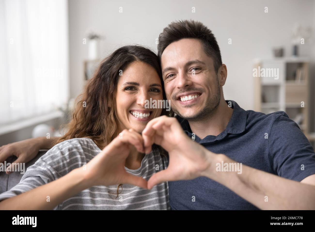 Ritratto alla testa moglie e marito che mostrano il simbolo del cuore con le dita Foto Stock