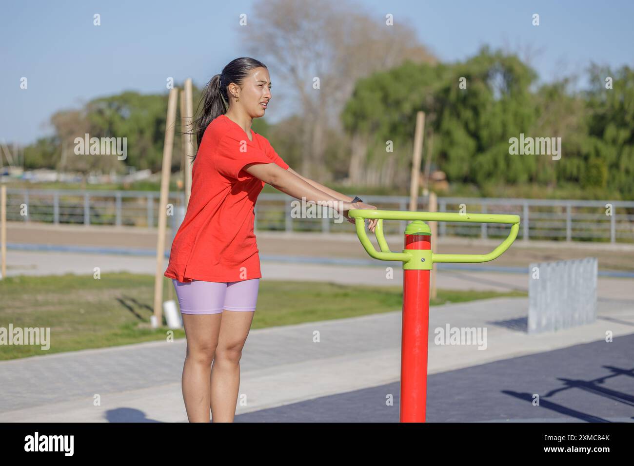 Ragazza latina su una macchina per esercizi in un parco pubblico. Foto Stock