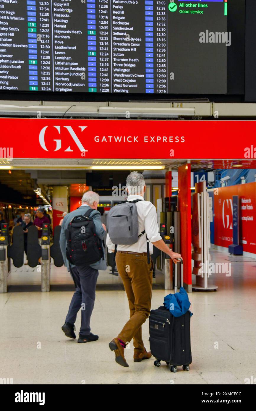 Londra, Inghilterra, Regno Unito - 27 giugno 2023: Persona che trasporta una valigia al treno espresso Gatwick alla stazione ferroviaria Victoria di Londra Foto Stock