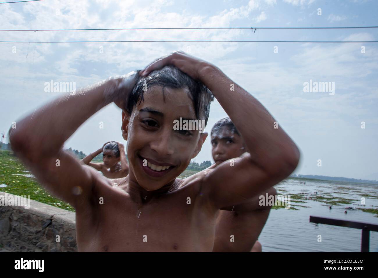 Srinagar, Jammu e Kashmir, India. 27 luglio 2024. I ragazzi kashmiri applicano lo shampoo, facendo un tuffo rinfrescante nelle acque del lago dal in una calda giornata estiva a Srinagar. Secondo un rapporto delle Nazioni Unite, l'India ha riportato 40.000 casi di sospetti colpi di calore e oltre 100 morti entro la metà di giugno di quest'anno, che ha sollecitato l'azione per frenare gli effetti del caldo estremo. (Immagine di credito: © Adil Abass/ZUMA Press Wire) SOLO PER USO EDITORIALE! Non per USO commerciale! Foto Stock