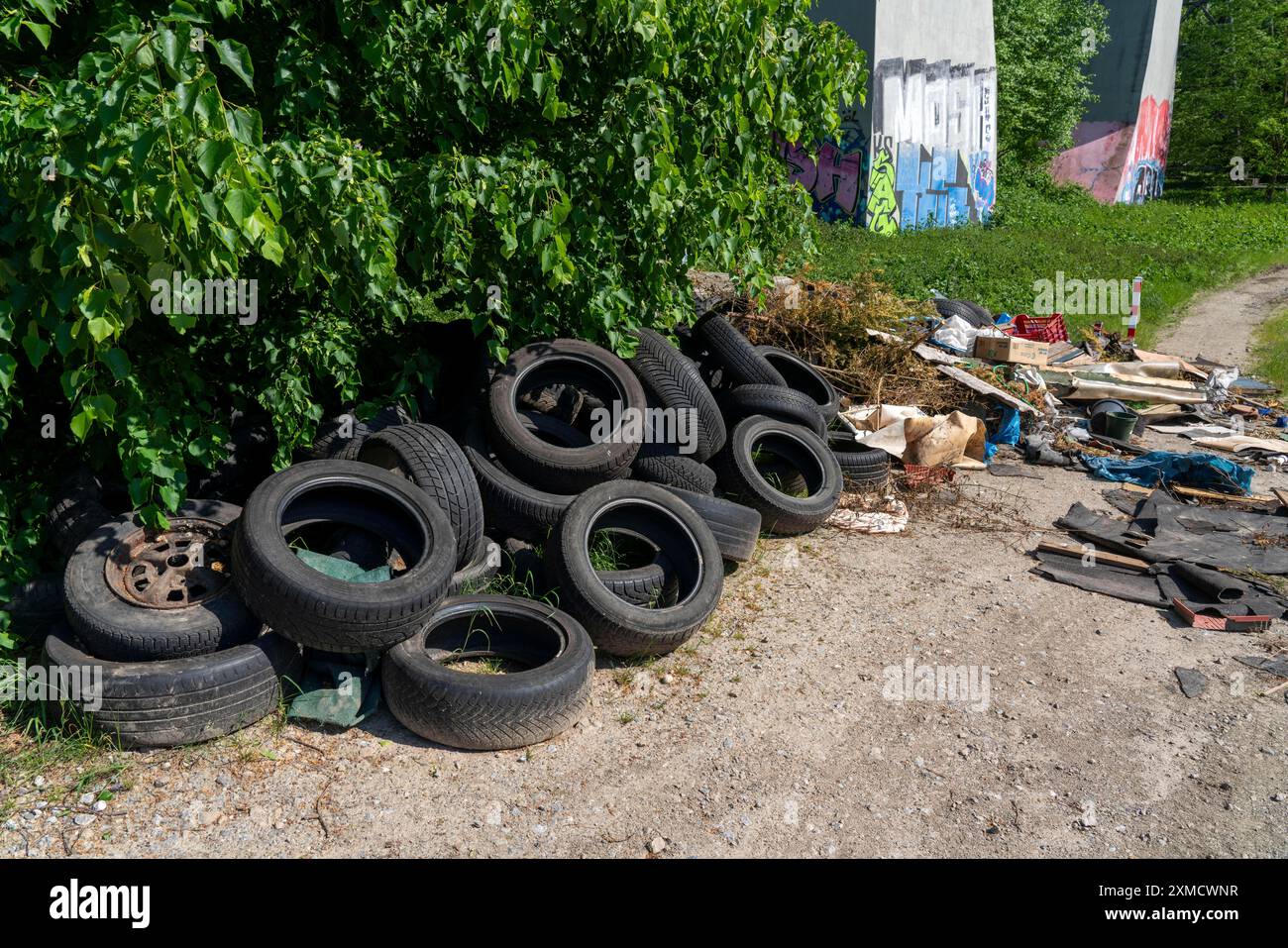 Rifiuti smaltiti illegalmente, pneumatici per automobili, macerie edili, rifiuti domestici, indumenti, su un sentiero vicino a una strada principale a Bochum, Renania settentrionale-Vestfalia Foto Stock