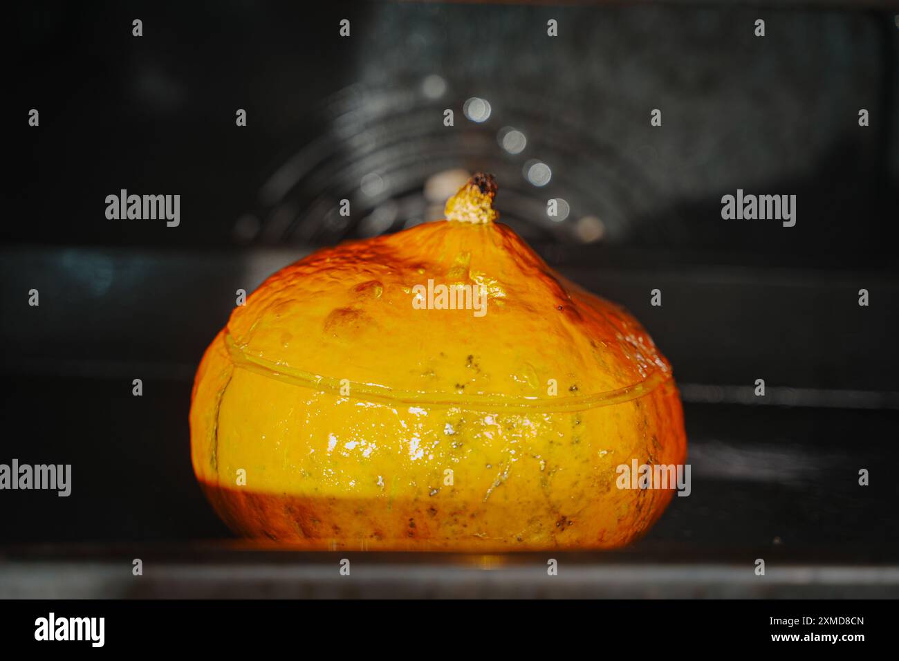 Cuocere la zucca nel forno. Una zucca intera con il taglio superiore viene cotta nel forno. Foto di alta qualità Foto Stock