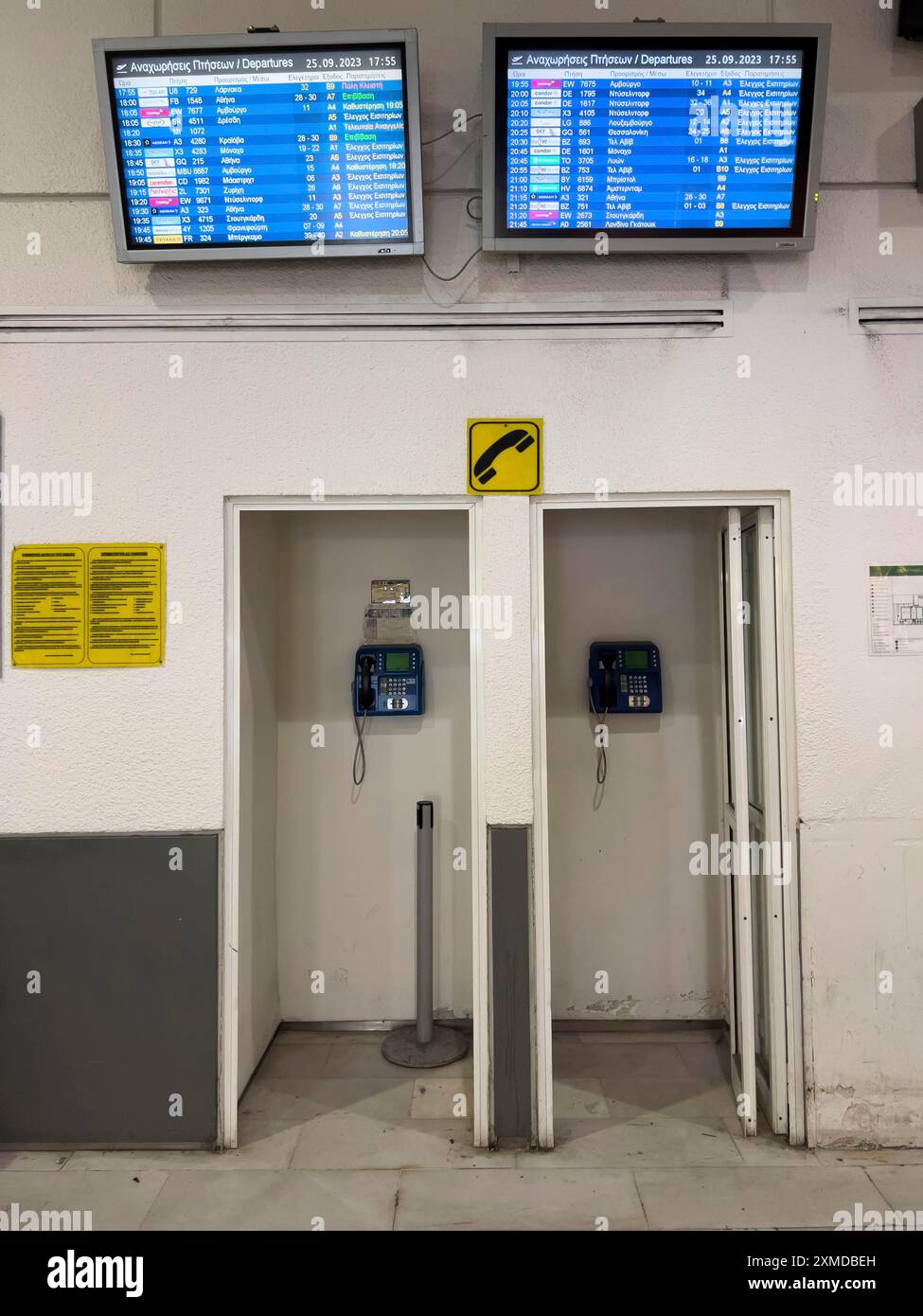 Telefoni a pagamento, cabine, nella sala partenze dell'aeroporto di Heraklion sull'isola greca di Creta, monitora con le informazioni sulla partenza Foto Stock