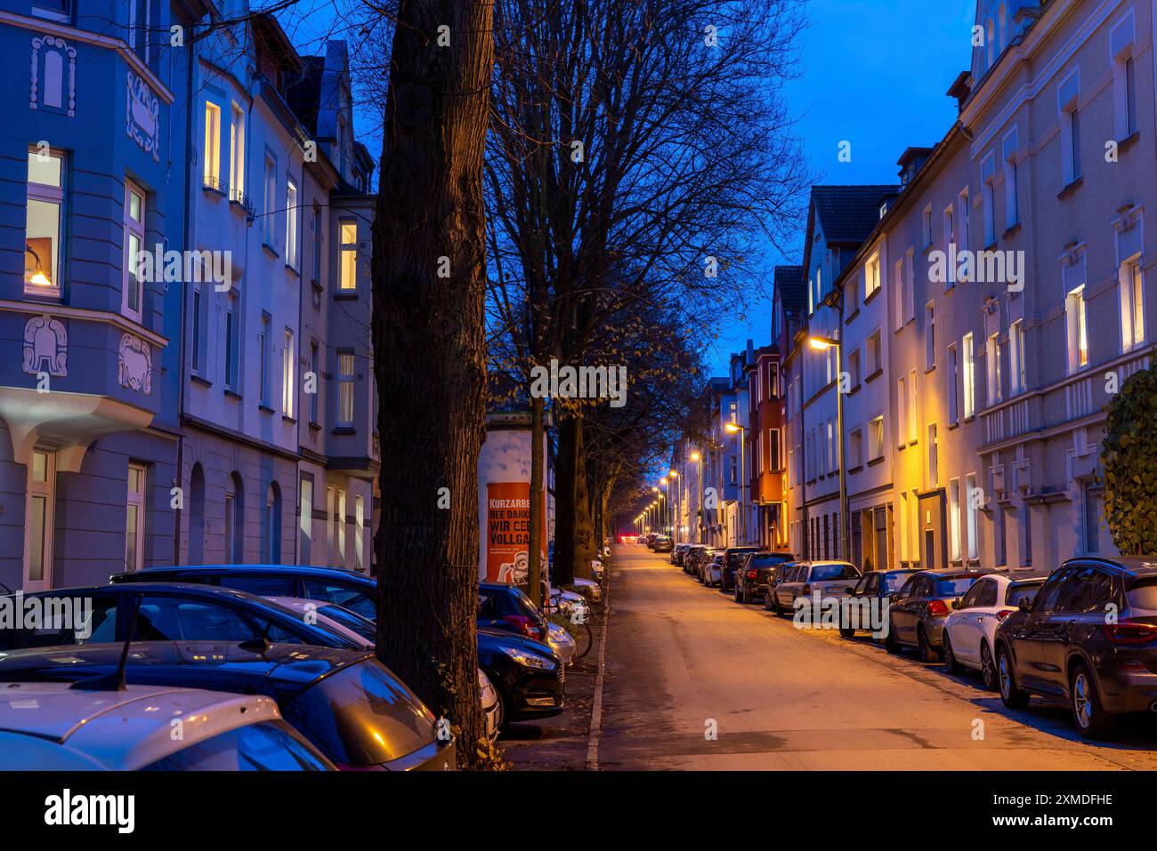 Strada residenziale, molti condomini in un quartiere residenziale, sera, illuminazione a lanterna, Essen, Renania settentrionale-Vestfalia, Germania Foto Stock