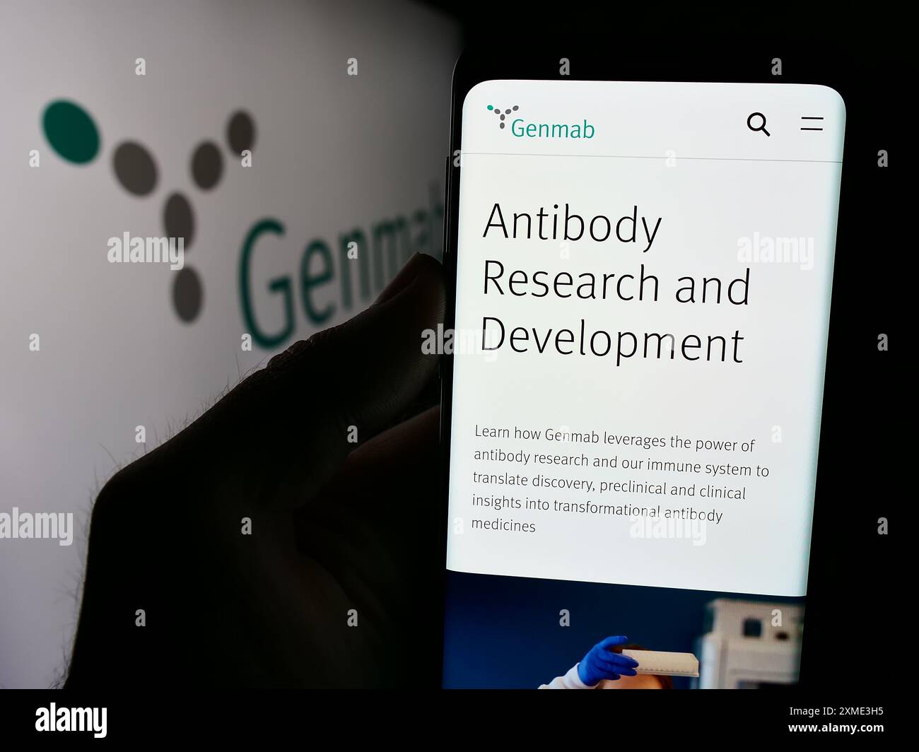 Persona che detiene un cellulare con pagina web della società danese di biotecnologie Genmab, COME di fronte al logo aziendale. Messa a fuoco al centro del display del telefono. Foto Stock