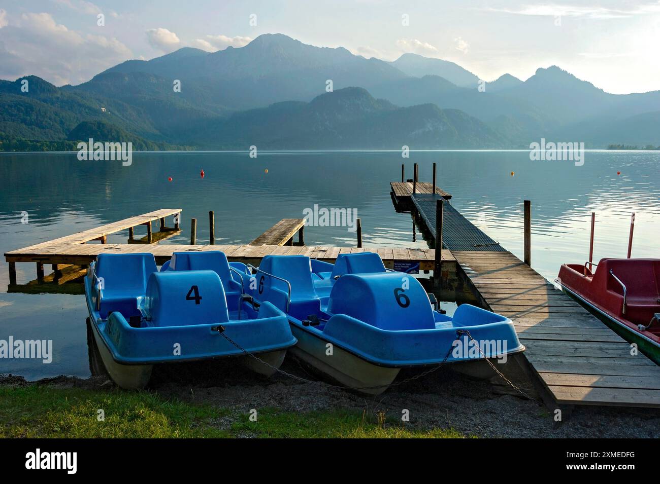 Pedalò sul molo alla luce della sera, noleggio barche, passeggiata sul lago di Kochel am SEE, lago Kochel, montagne Herzogstand, Roetelstein Foto Stock