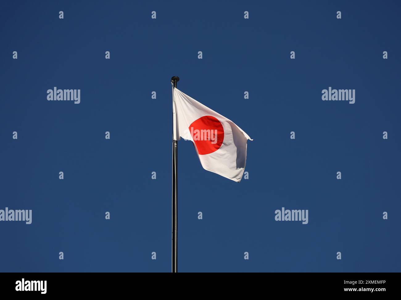 Bandiera giapponese che sventola nel vento contro un cielo blu Foto Stock