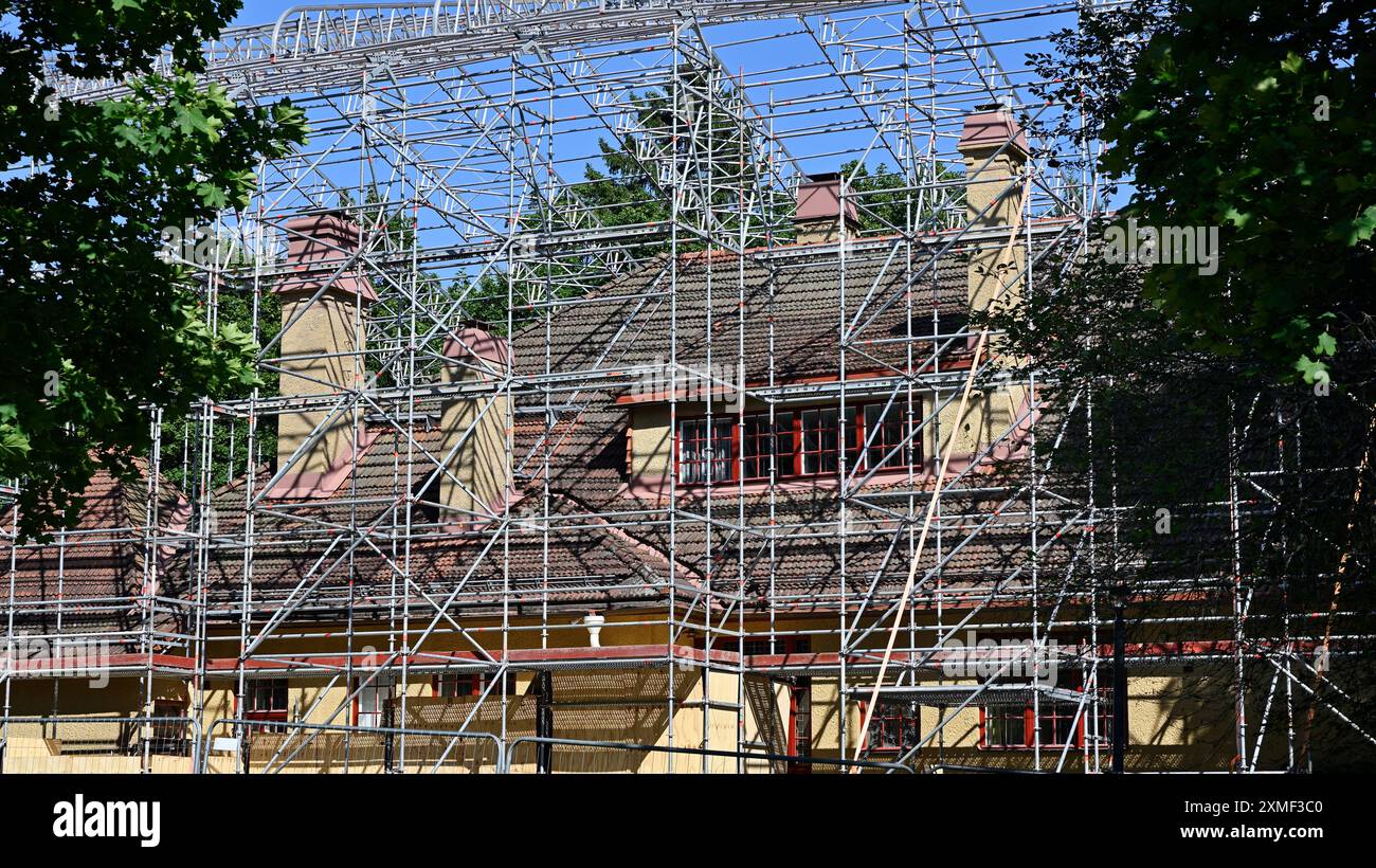 Una casa in fase di ristrutturazione è circondata da un'ampia struttura a impalcature. L'edificio, caratterizzato da un tetto piastrellato e diversi camini, e' in t Foto Stock