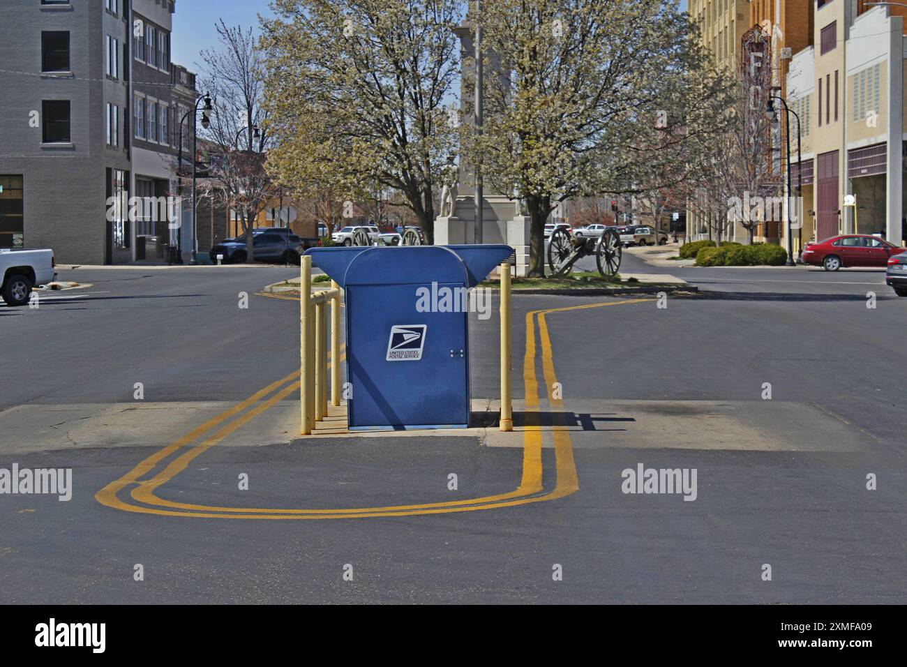 Una USPS mail Box in strada con edifici e alberi all'aperto Foto Stock