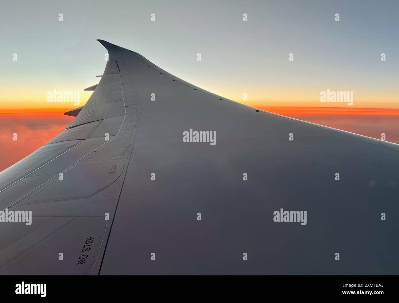 Al tramonto le nuvole diventano rosse sotto le ali di un Boeing 787 che attraversa Cape Cod. Foto Stock