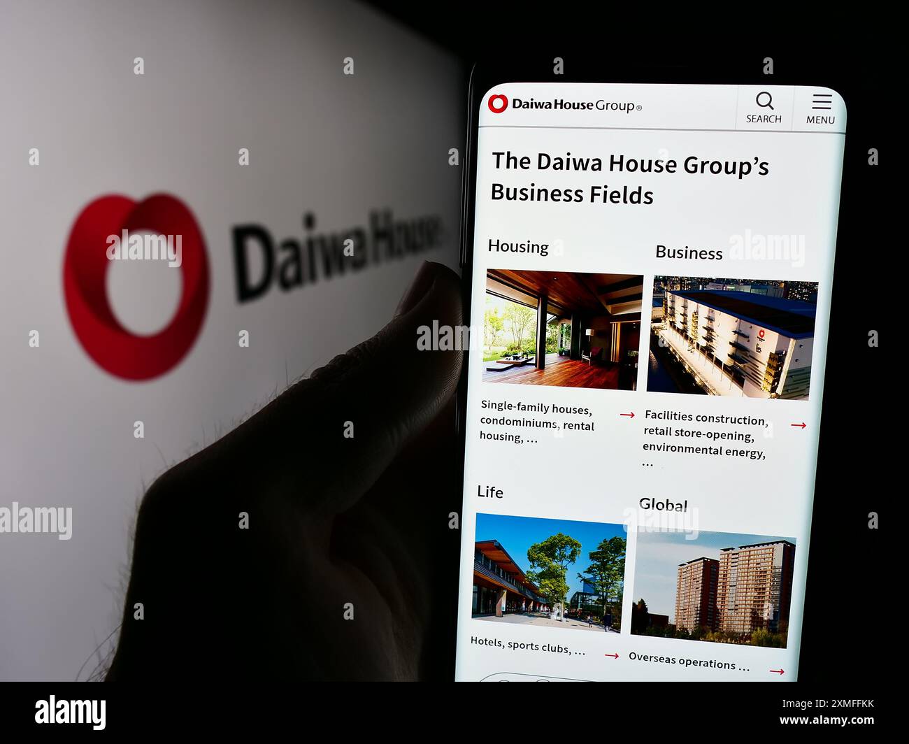 Persona che detiene il cellulare con la pagina web della società di costruzioni Daiwa House Industry Co. Ltd. Davanti al logo. Messa a fuoco al centro del display del telefono. Foto Stock