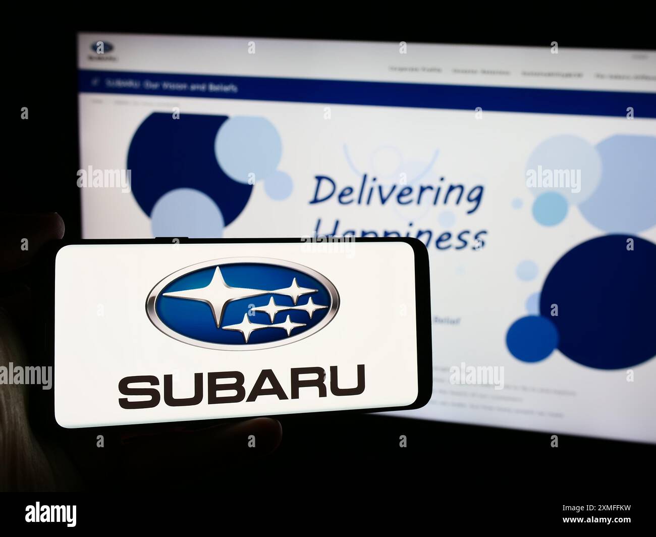 Persona che possiede un telefono cellulare con il logo della società giapponese Subaru Corporation di fronte alla pagina Web aziendale. Mettere a fuoco il display del telefono. Foto Stock