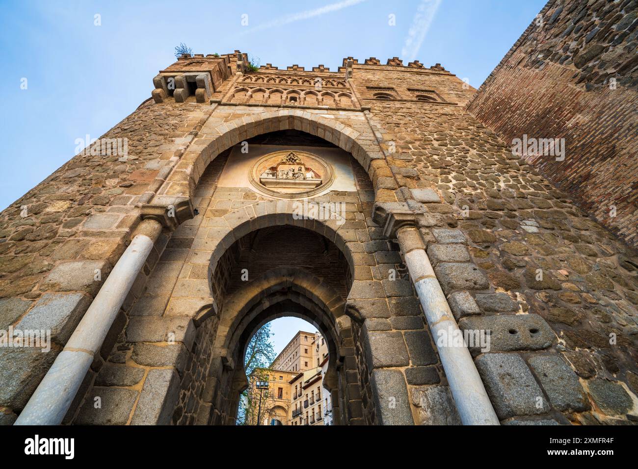Puerta del Sol, una porta medievale di Toledo, in Spagna, in una giornata di sole. Il medaglione sopra l'arco raffigura l'ordinazione del santo della città Foto Stock