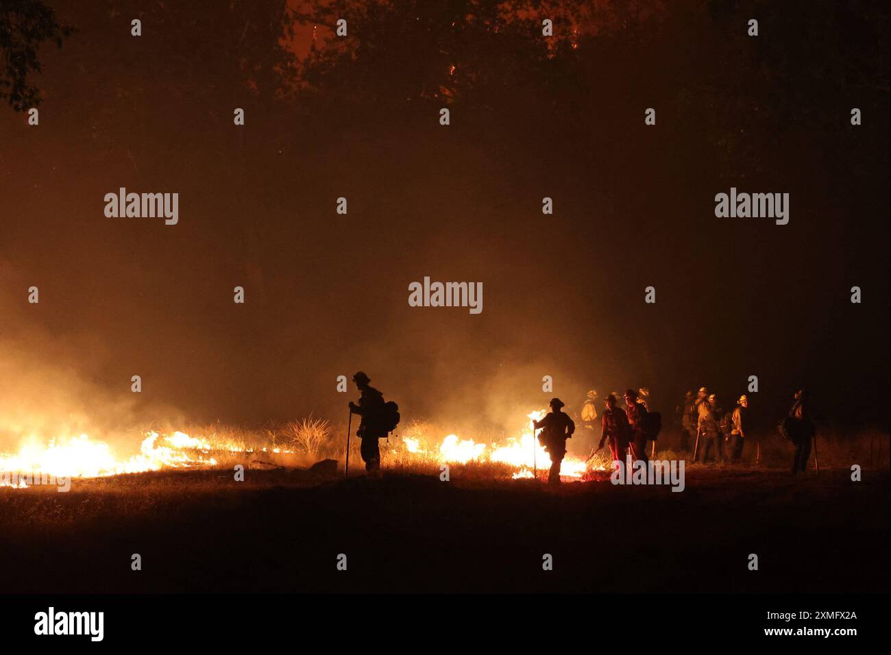 Le foto mostrano i vigili del fuoco che combattono contro le fiamme il 26 luglio 2024 in California, USA. Il più grande incendio attivo della California è esploso di dimensioni venerdì sera, crescendo rapidamente in mezzo al combustibile secco e minacciando migliaia di case mentre i vigili del fuoco si sono messi in difficoltà per affrontare il pericolo. L'intensità e la rapida diffusione del fuoco del Parco portarono i vigili del fuoco a fare confronti sgraditi con il mostruoso fuoco del campo, che bruciò fuori controllo nel vicino Paradise nel 2018, uccidendo 85 persone e bruciando 11.000 case. Più di 130 strutture sono state distrutte da questo incendio finora, e altre migliaia rimangono tre Foto Stock