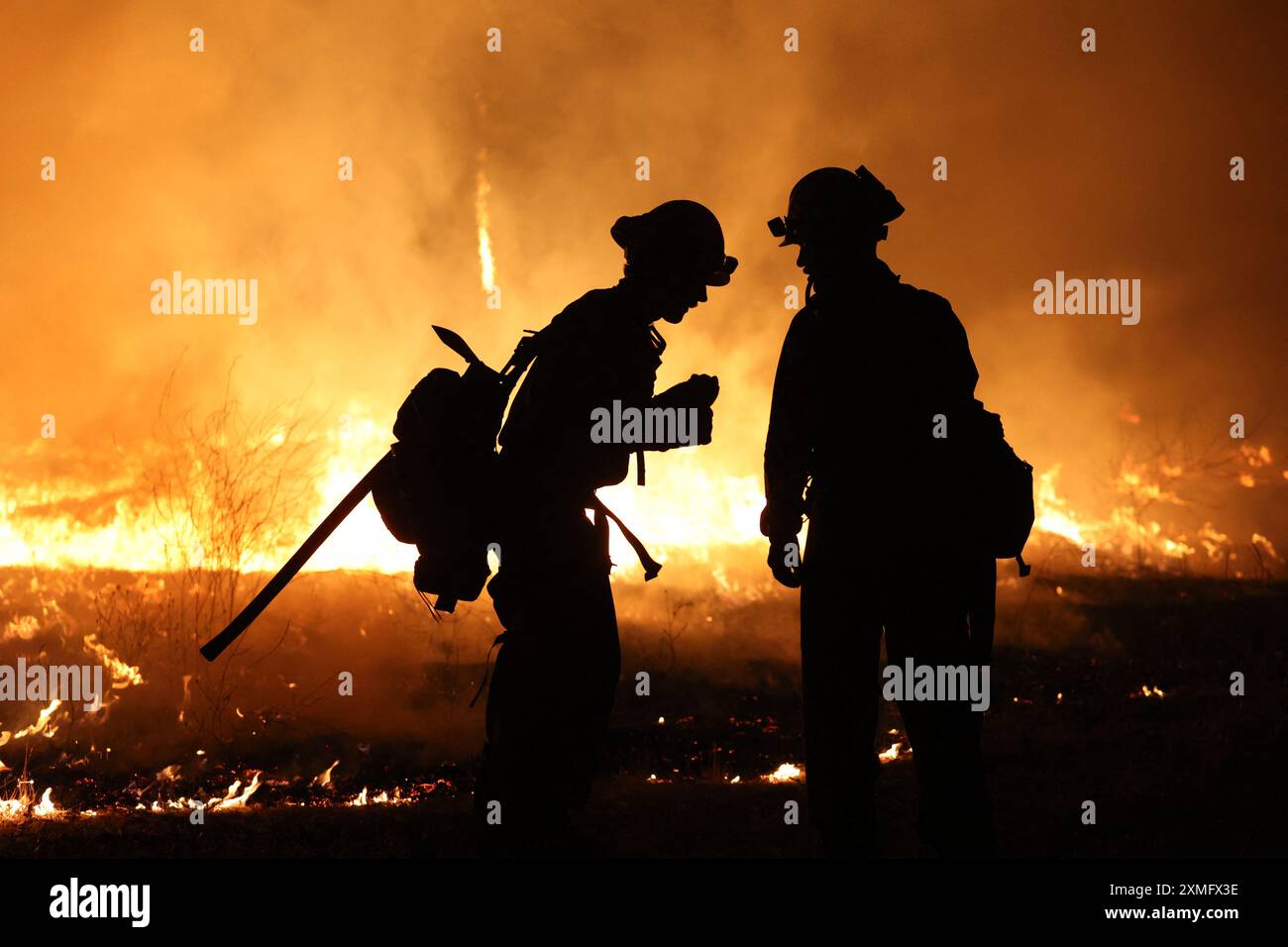 Le foto mostrano i vigili del fuoco che combattono contro le fiamme il 26 luglio 2024 in California, USA. Il più grande incendio attivo della California è esploso di dimensioni venerdì sera, crescendo rapidamente in mezzo al combustibile secco e minacciando migliaia di case mentre i vigili del fuoco si sono messi in difficoltà per affrontare il pericolo. L'intensità e la rapida diffusione del fuoco del Parco portarono i vigili del fuoco a fare confronti sgraditi con il mostruoso fuoco del campo, che bruciò fuori controllo nel vicino Paradise nel 2018, uccidendo 85 persone e bruciando 11.000 case. Più di 130 strutture sono state distrutte da questo incendio finora, e altre migliaia rimangono tre Foto Stock