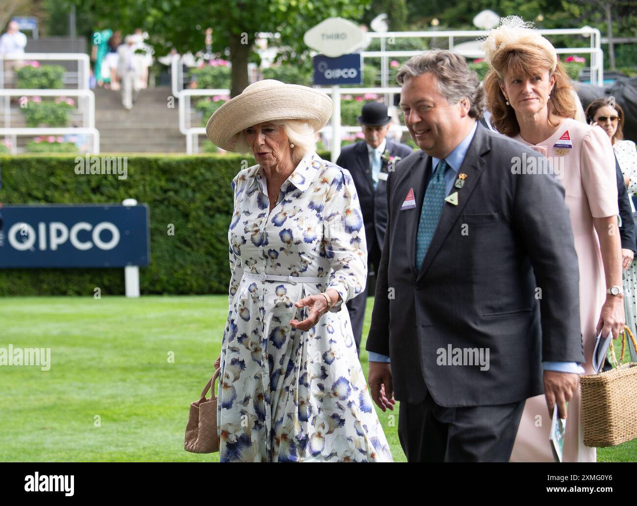 Ascot, Berkshire, Regno Unito. 27 luglio 2024. Sua Maestà la Regina Camilla nel Parade Ring all'Ascot Racecourse per il QIPCO King George Day insieme a Sir Francis Brooke, Rappresentante e Presidente di sua Maestà. La regina indossava un grazioso abito estivo floreale bianco con una stampa a Iris blu della designer reale Suzannah London. Sua Maesta' indossava anche un ampio cappello a tesa e portava una piccola borsa biege. La regina Camilla indossava orecchini a goccia di perle e una collana d'oro. Il cavallo della Regina ammanettato corse al Sodexo Live! Principessa Margaret Stakes, ma non e' stata collocata. Crediti: Maureen McLean/Alamy Live New Foto Stock