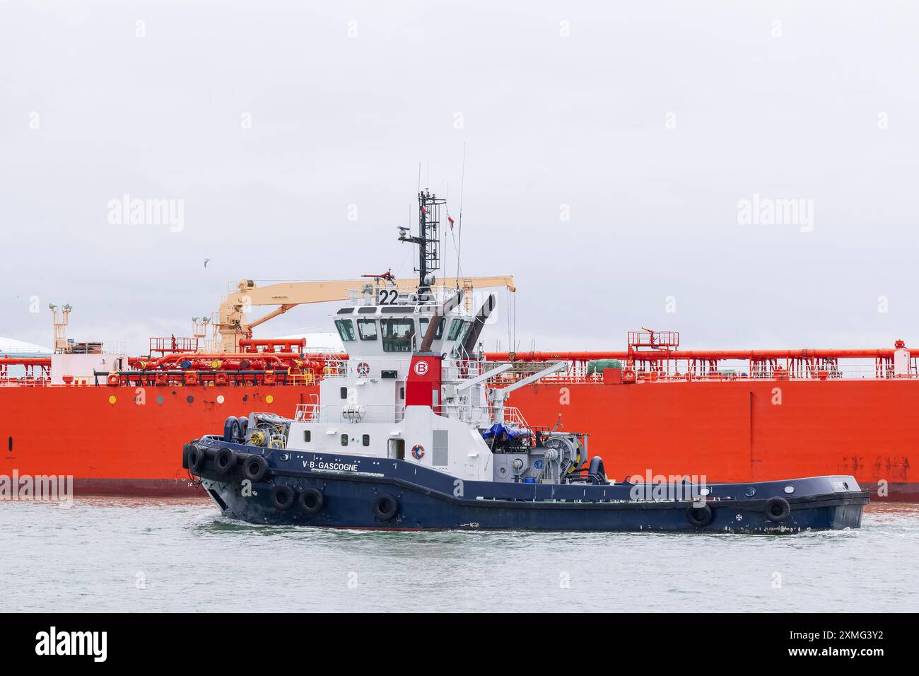 Le Havre, Francia - Vista sul rimorchiatore del porto VB GASCOGNE attraversa di fronte ad una petroliera al porto di le Havre con un cielo grigio. Foto Stock