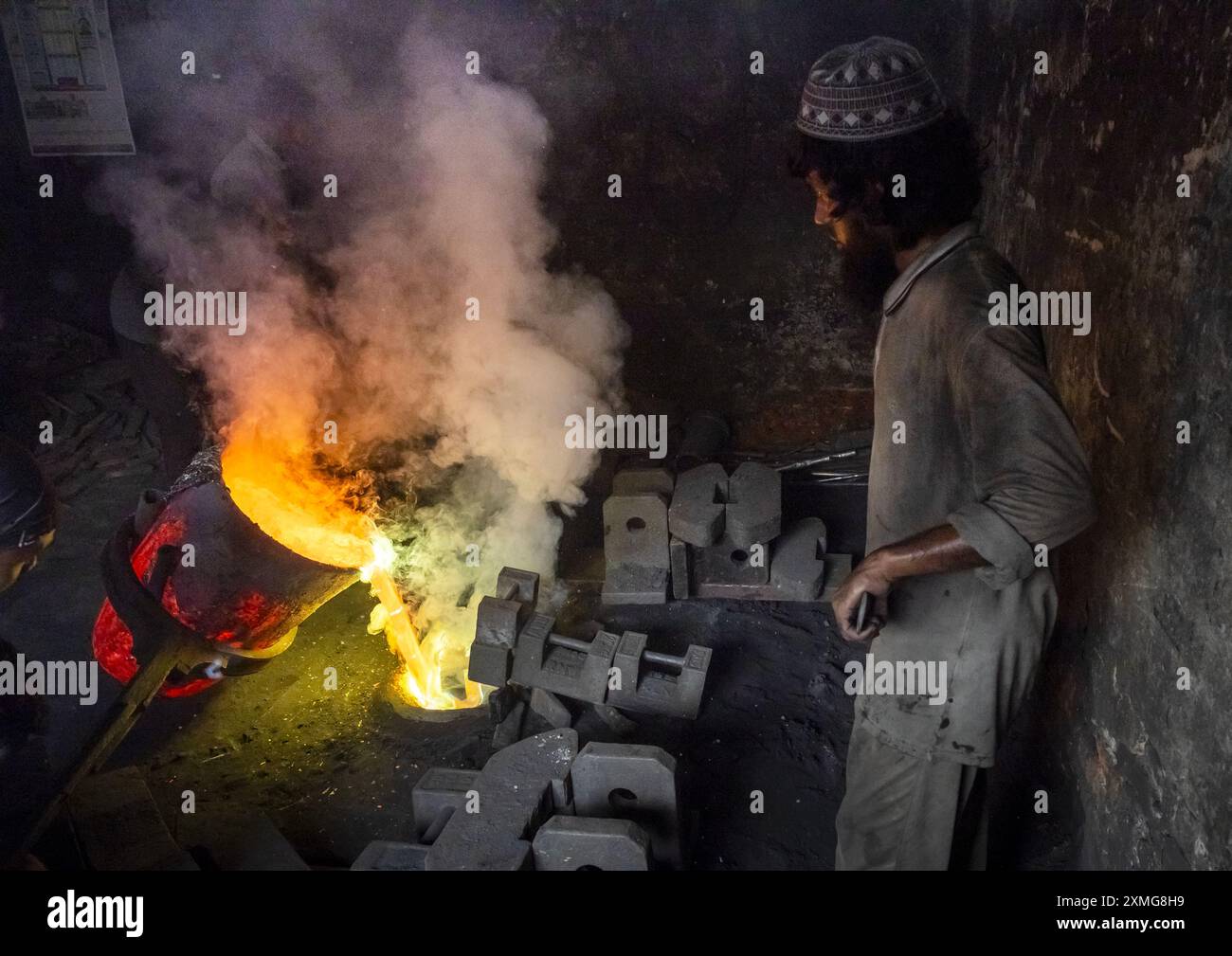 Uomo del Bangladesh che mette acciaio fuso in uno stampo presso il cantiere navale di Dacca, Divisione di Dacca, Keraniganj, Bangladesh Foto Stock