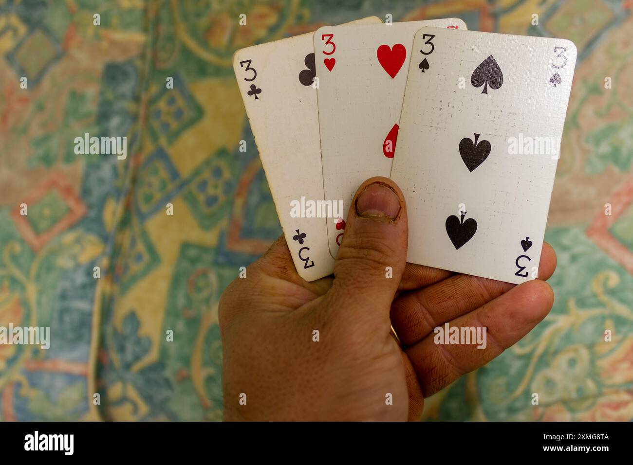tre carte da gioco con il numero tre in mano umana Foto Stock