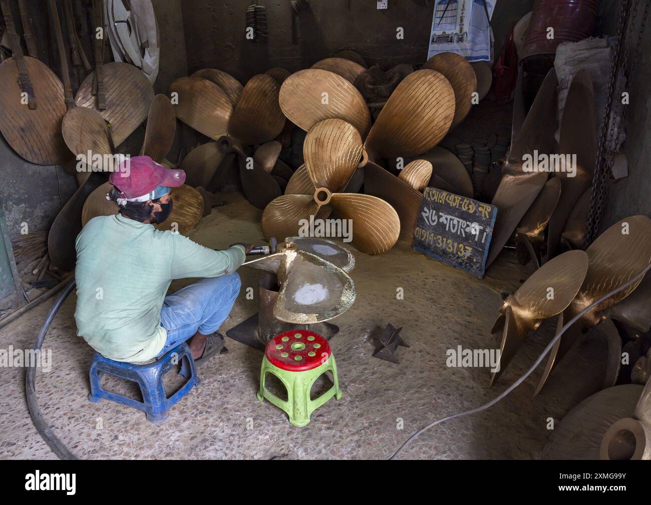Lavoratore del cantiere bengalese che lucida un'elica, Divisione di Dacca, Keraniganj, Bangladesh Foto Stock
