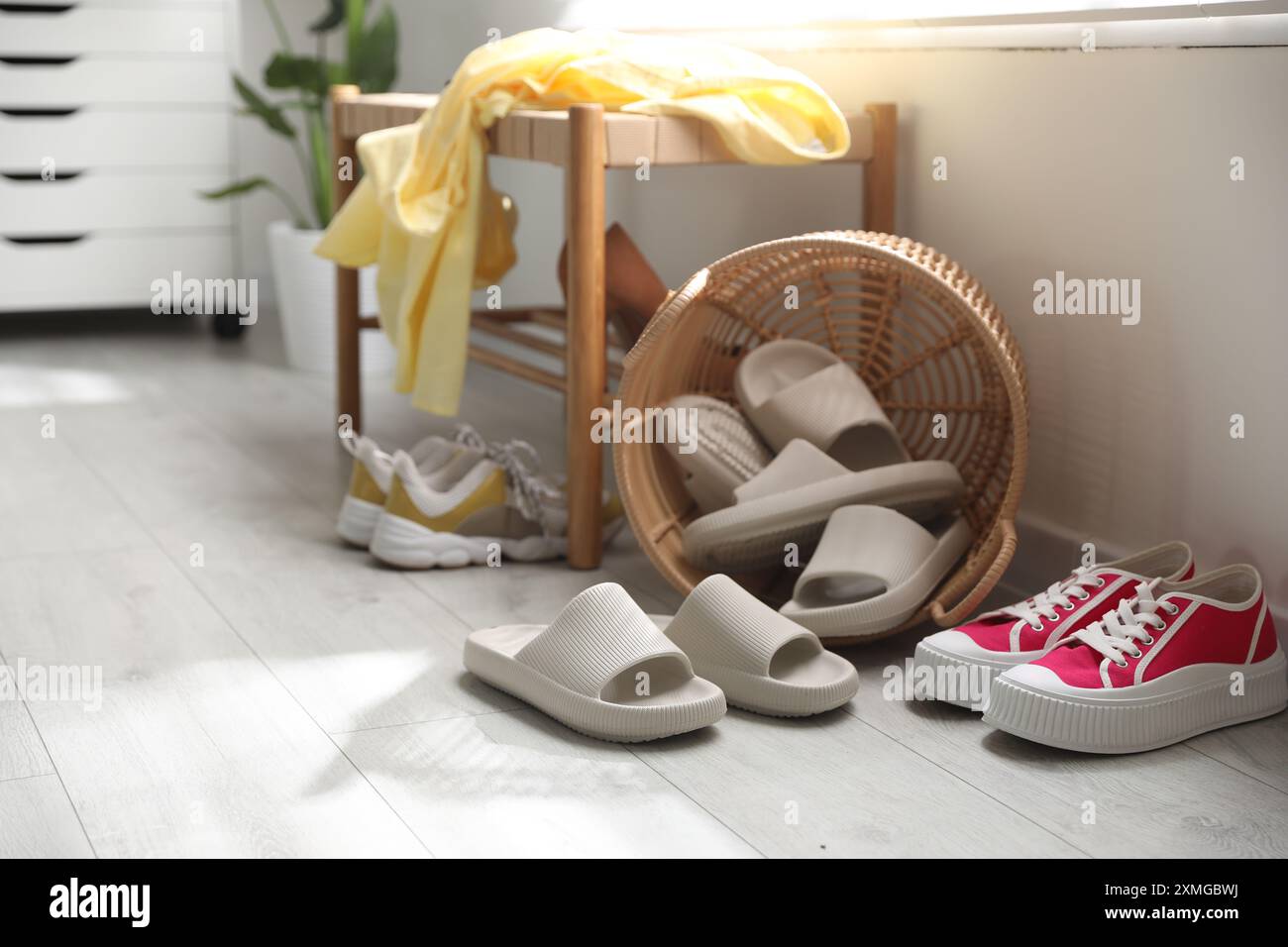 Cestino con pantofole per gli ospiti e scarpe da ginnastica all'ingresso di casa Foto Stock