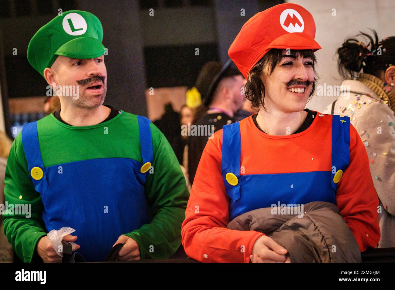 Due persone allegri in costumi ispirati a Mario in un evento vivace. I personaggi abbinati sono vestiti alla moda come personaggi iconici dei videogiochi Foto Stock