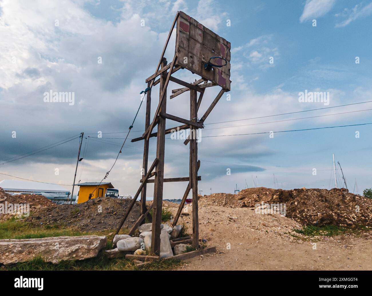 Il canestro da basket della comunità si erge alto in una baraccopoli filippina tra strutture incompiute e cielo coperto Foto Stock