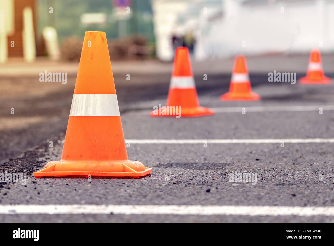 Vista ravvicinata dei coni stradali arancioni allineati su una strada asfaltata, indicante un'area di costruzione o manutenzione. Foto Stock