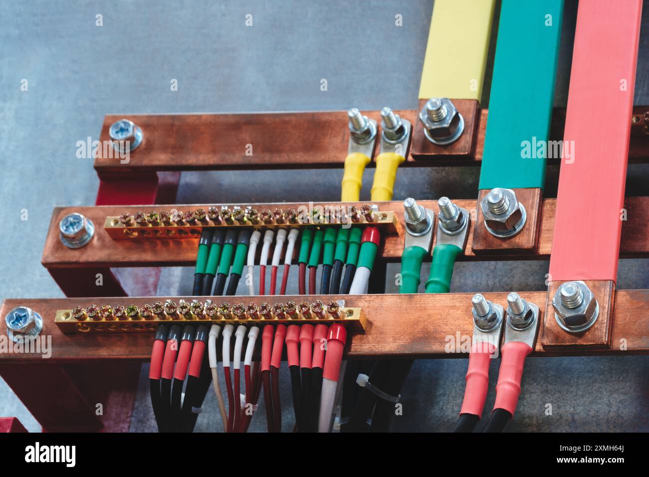 Molti fili elettrici di alimentazione fili multicolore e dadi collegati a barre di distribuzione in metallo di rame tre fasi elettriche ad alta tensione industriale. Elettricità Foto Stock