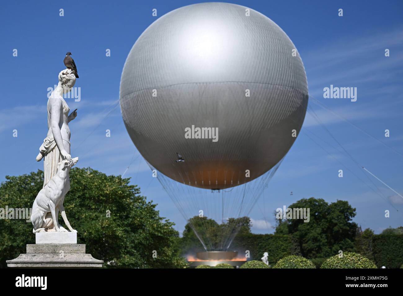 Parigi, Francia. 28 luglio 2024. Olympia, Parigi 2024, un piccione siede su una scultura accanto a un pallone aerostatico che trasporta il calderone con la fiamma olimpica. Crediti: Sven Hoppe/dpa/Alamy Live News Foto Stock