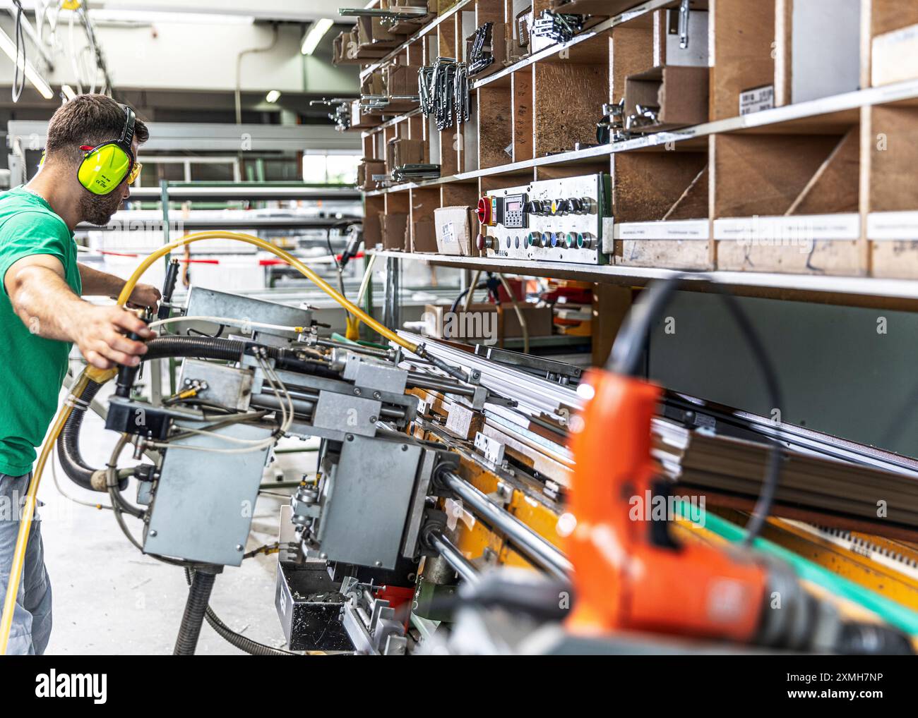 Lavoratore qualificato in una fabbrica di finestre, in piedi di fronte a una macchina Foto Stock