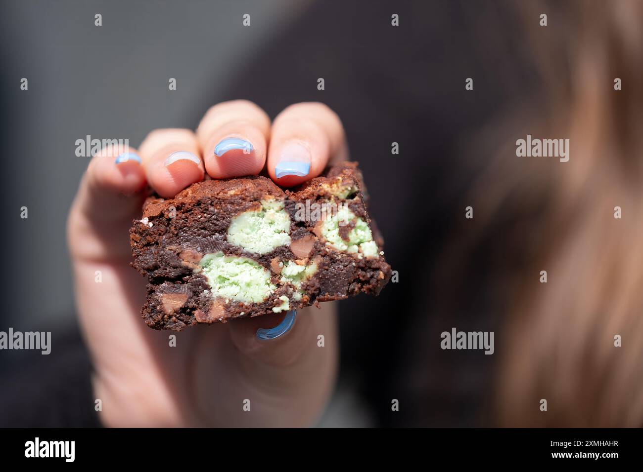 Un brownie alla menta appena fatto in casa che viene tenuto in mano e mostrato alla telecamera, il brownie è ancora caldo e gooey. una delizia indulgente Foto Stock