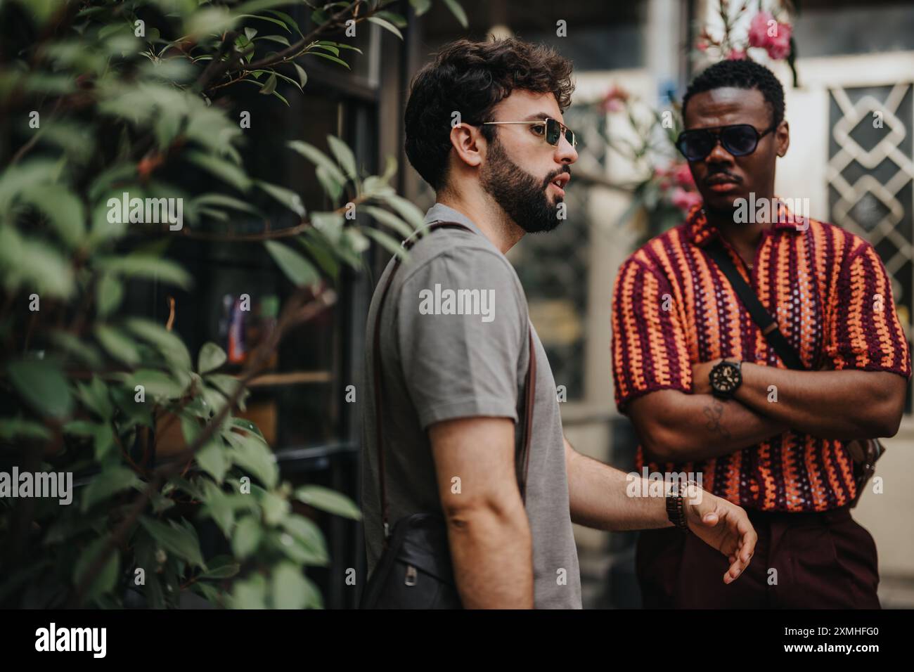 Due uomini d'affari in una discussione informale all'aperto con occhiali da sole e abbigliamento colorato Foto Stock