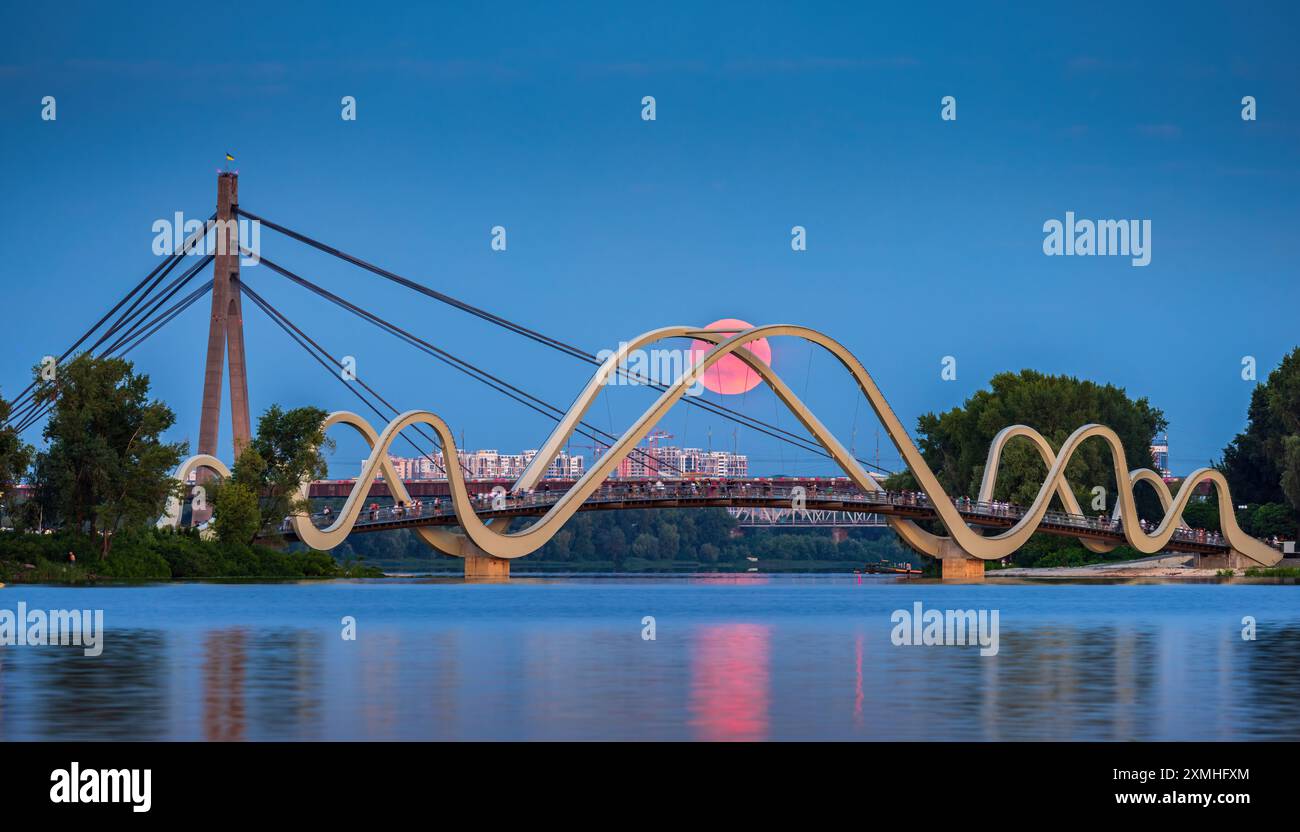 Pink Full Moon sorge sullo sfondo di un ponte pedonale nel distretto di Obolon, Kiev, Ucraina Foto Stock