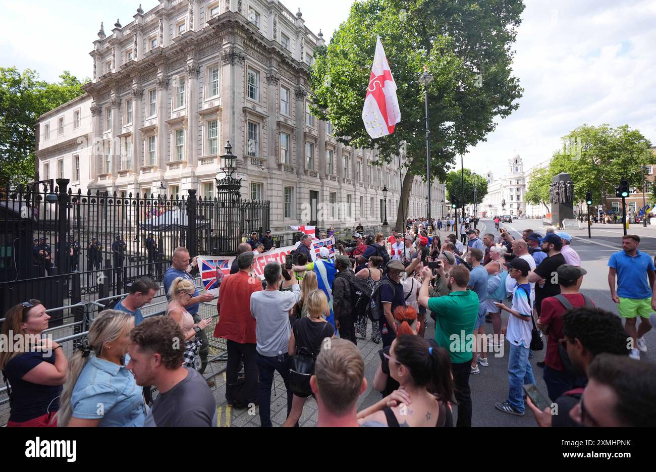 I manifestanti fuori Downing Street a Londra protestarono contro il presunto arresto di Tommy Robinson. Tommy Robinson è stato arrestato secondo le leggi antiterrorismo, secondo il suo conto Verified X. La sua detenzione segue una denuncia per un film che sarebbe stato mostrato alla folla durante una marcia nel centro di Londra di sabato guidata da Mr Robinson, il cui vero nome è Stephen Yaxley Lennon. Data foto: Domenica 28 luglio 2024. Foto Stock