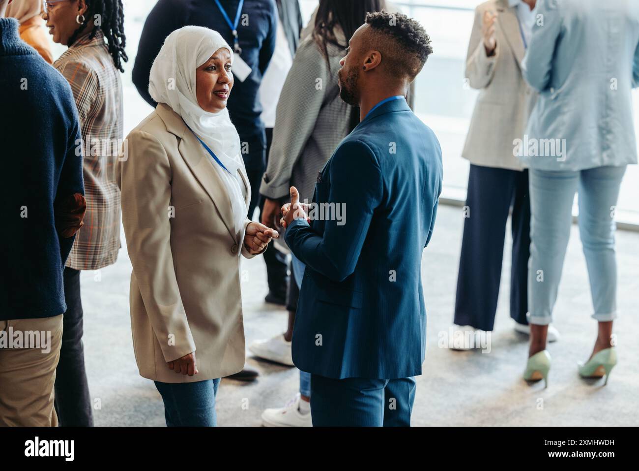 Un gruppo diversificato di professionisti che interagiscono in rete e interagiscono in occasione di una conferenza aziendale. Le persone sono impegnate in conversazioni e creano connessioni Foto Stock