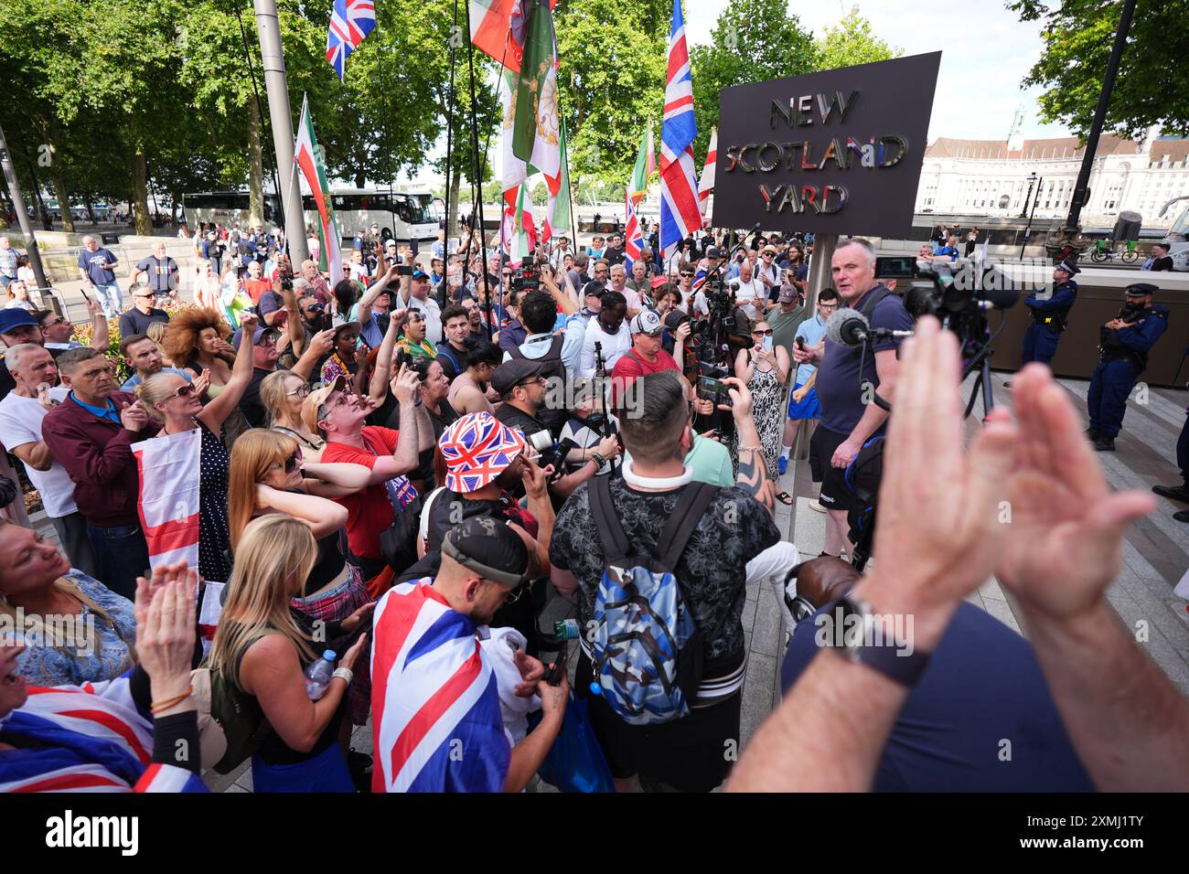 Manifestanti fuori New Scotland Yard a Londra per protestare contro il presunto arresto di Tommy Robinson. Tommy Robinson è stato arrestato secondo le leggi antiterrorismo, secondo il suo conto Verified X. La sua detenzione segue una denuncia per un film che sarebbe stato mostrato alla folla durante una marcia nel centro di Londra di sabato guidata da Mr Robinson, il cui vero nome è Stephen Yaxley Lennon. Data foto: Domenica 28 luglio 2024. Foto Stock
