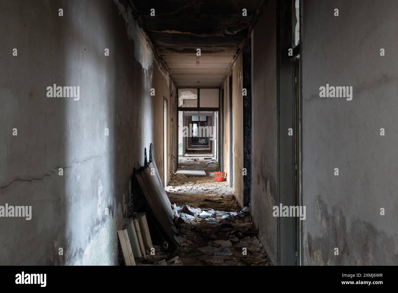 Corridoio disordinato in un edificio di uffici abbandonato con tracce di incendio doloso e pareti sbucciate Foto Stock