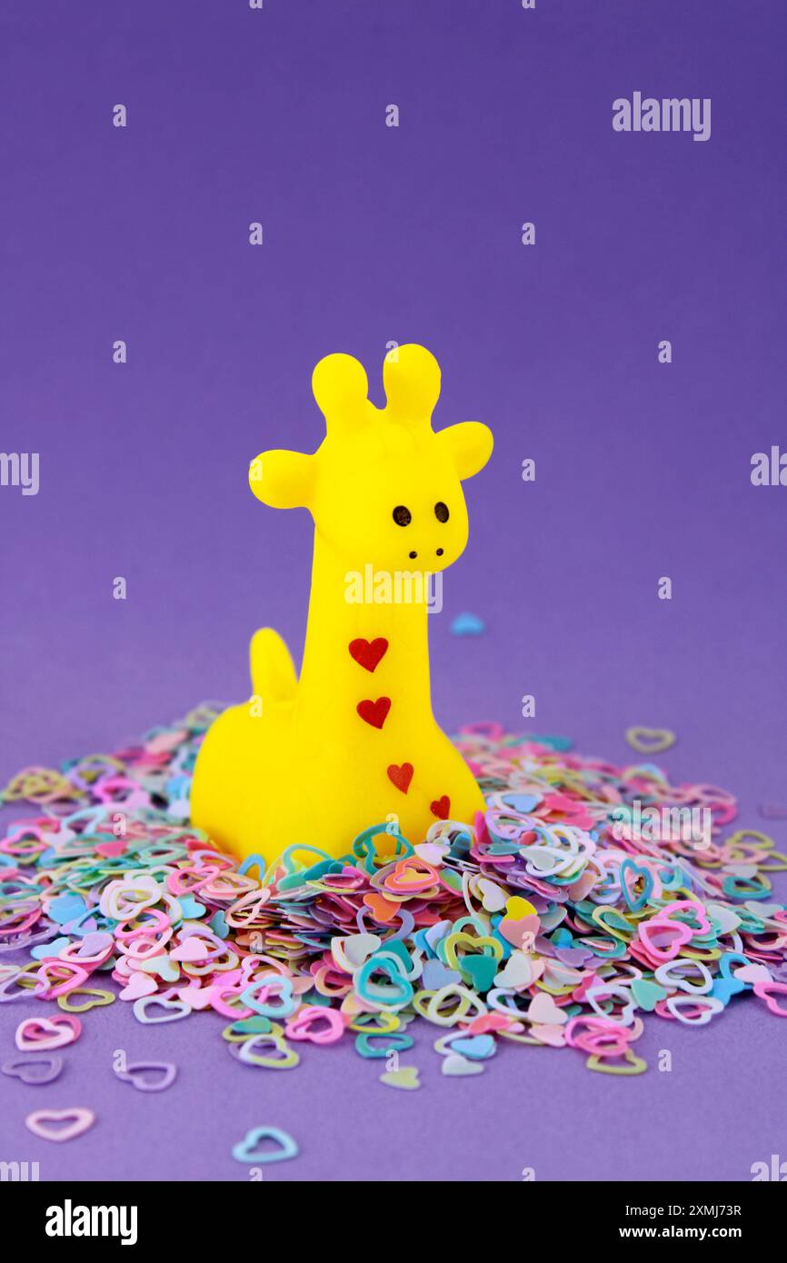Simpatica giraffa giocattolo circondata da cuori Foto Stock