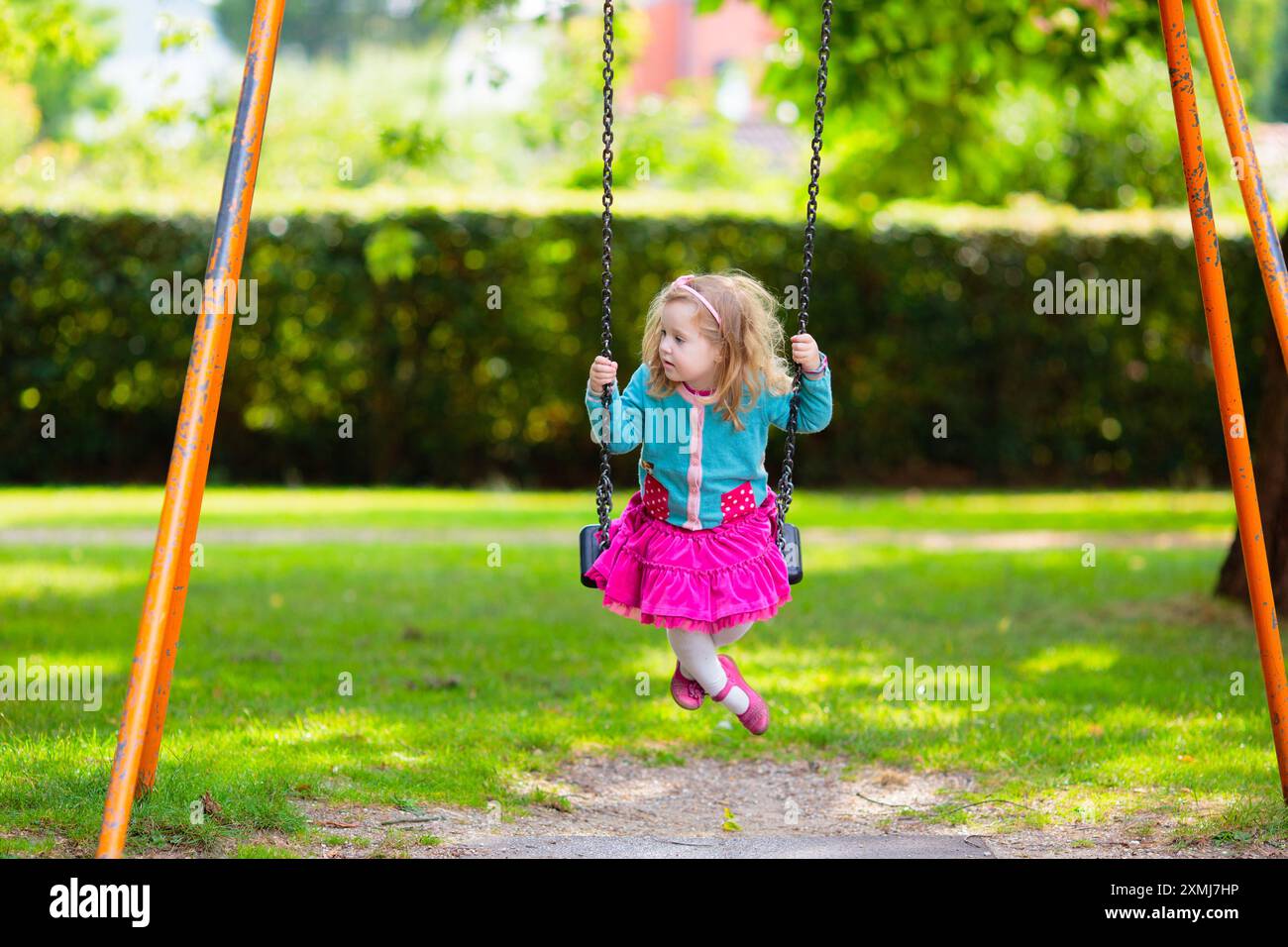 I bambini esplorano la natura. I bambini giocano nel parco soleggiato. Bambini nel parco giochi dello splendido parco estivo. Divertimento all'aperto per tutta la famiglia. Ragazzino su swing e scivolo. Foto Stock