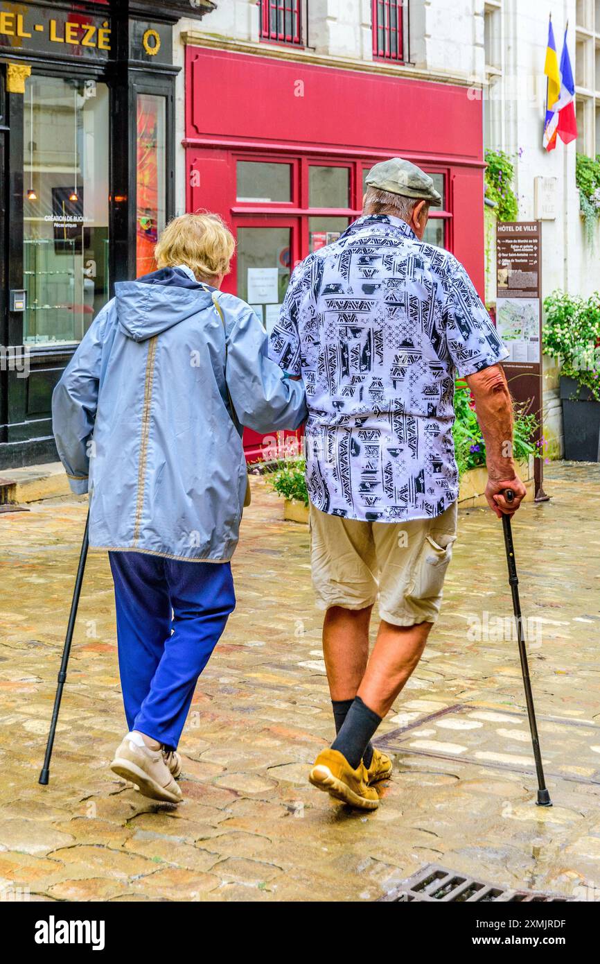 Coppia di anziani con bastoni da passeggio braccio in braccio nel centro città - Loches, Indre-et-Loire (37), Francia. Foto Stock