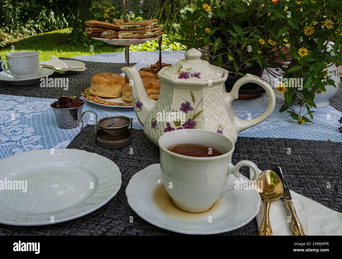 Tradizionale tè inglese panna con scones e cetrioli sandwich in un patio giardino Foto Stock