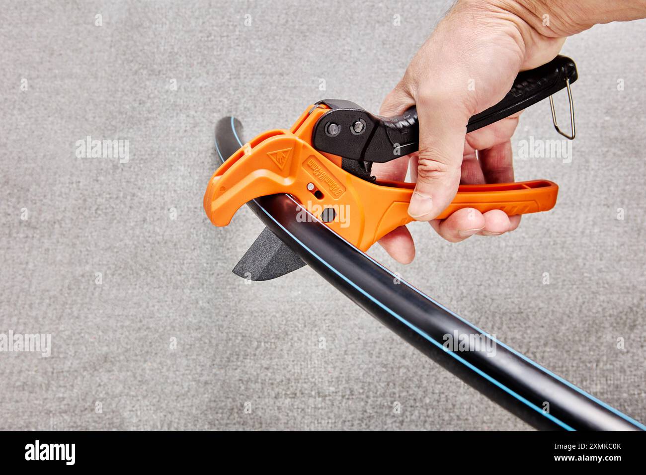 Le cesoie per tubi in plastica a mano tagliano il tubo in HDPE. Foto Stock