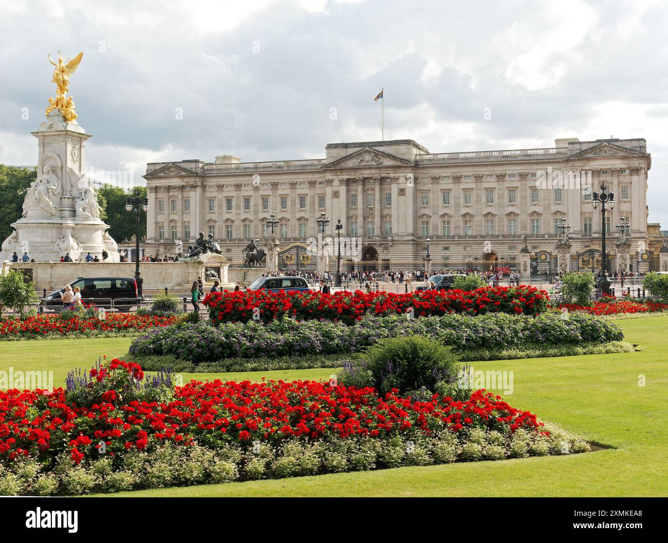 Vista dell'affollato Buckingham Palace a Londra con il Victoria Memorial e i fiori colorati del Constitution Hill Memorial Garden in primo piano Foto Stock