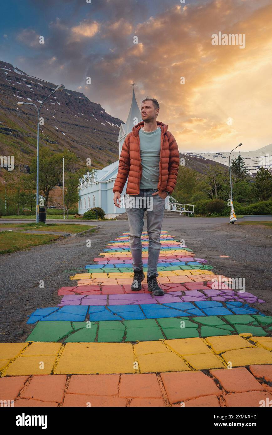 Uomo sul sentiero arcobaleno che conduce alla Chiesa Bianca di Seydisfjordur, Islanda Foto Stock