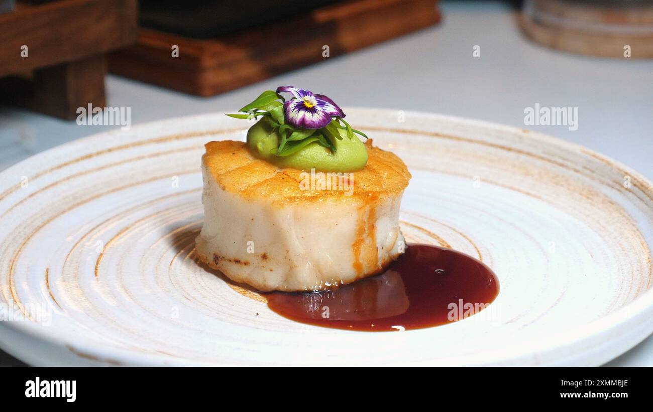 Piatto di capesante per buongustai con splendide decorazioni, ornato da verdi e. Foto Stock