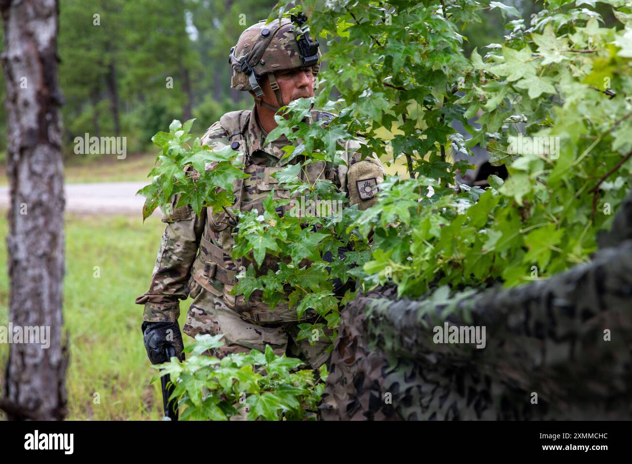 Il sergente dello staff dell'esercito degli Stati Uniti Leon Lucero del 1st Battalion, 200th Infantry Regiment, New Mexico Army National Guard copre il suo veicolo e le sue attrezzature in mimetizzazione dopo che la sua unità 'salta' in una nuova posizione mentre si trova al Joint Readiness Training Center (JRTC) durante la rotazione JRTC 24-09 a Fort Johnson, Laos, 26 luglio 2024. L'obiettivo del JRTC è creare ambienti realistici che aiutino a preparare le unità per operazioni complesse in un'ampia varietà di scenari. (Foto della Guardia Nazionale dell'Oregon Army di Jason Morgan, 115th Mobile Public Affairs Detachment) Foto Stock